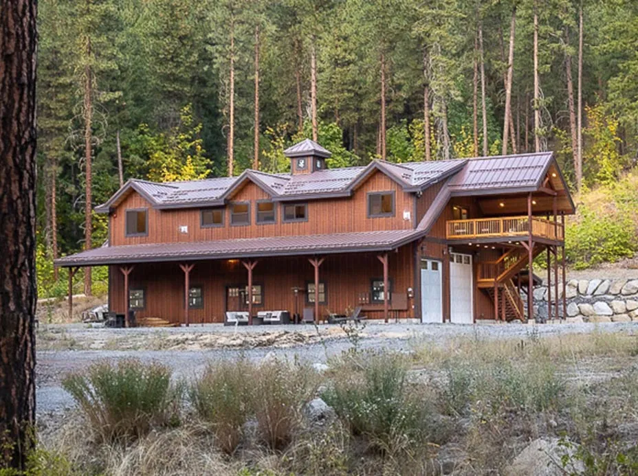 A board-and-batten barn home with a cupola, shed dormers and a covered porch.